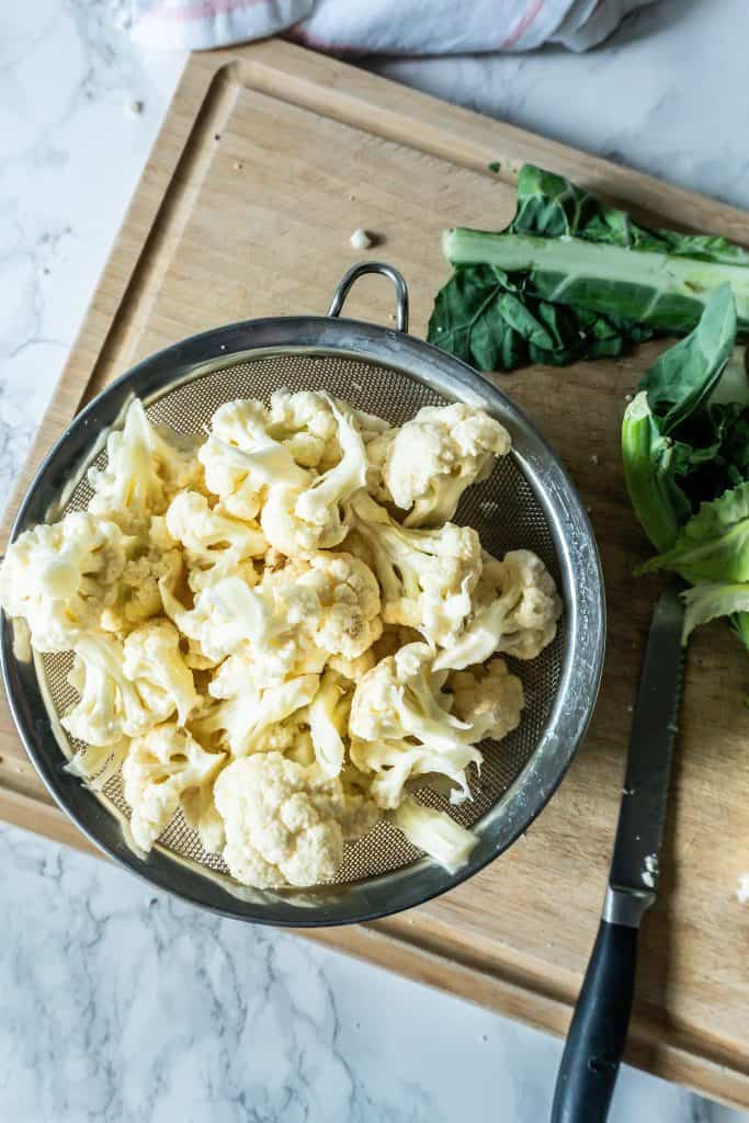 Cauliflower in individual pieces, in a sieve ready for washing