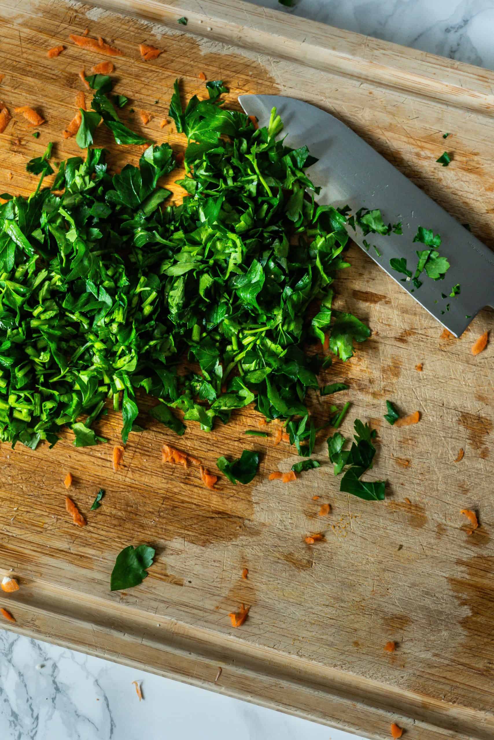 Parsley being chopped on a cutting board