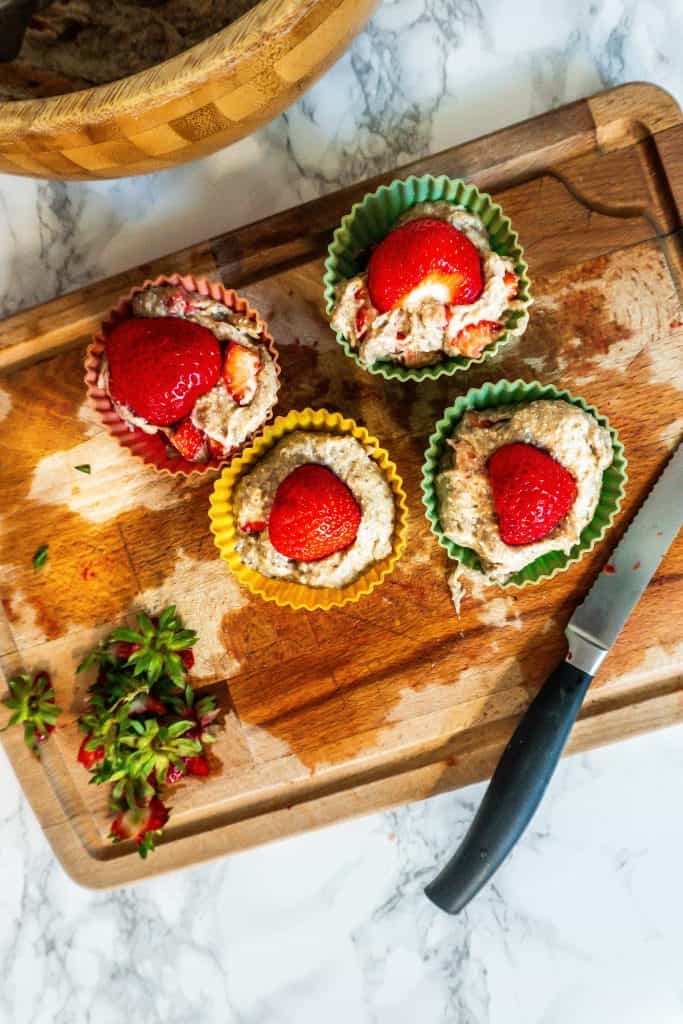 Adding one sliced strawberry on top of the the Strawberry Banana Muffins before baking