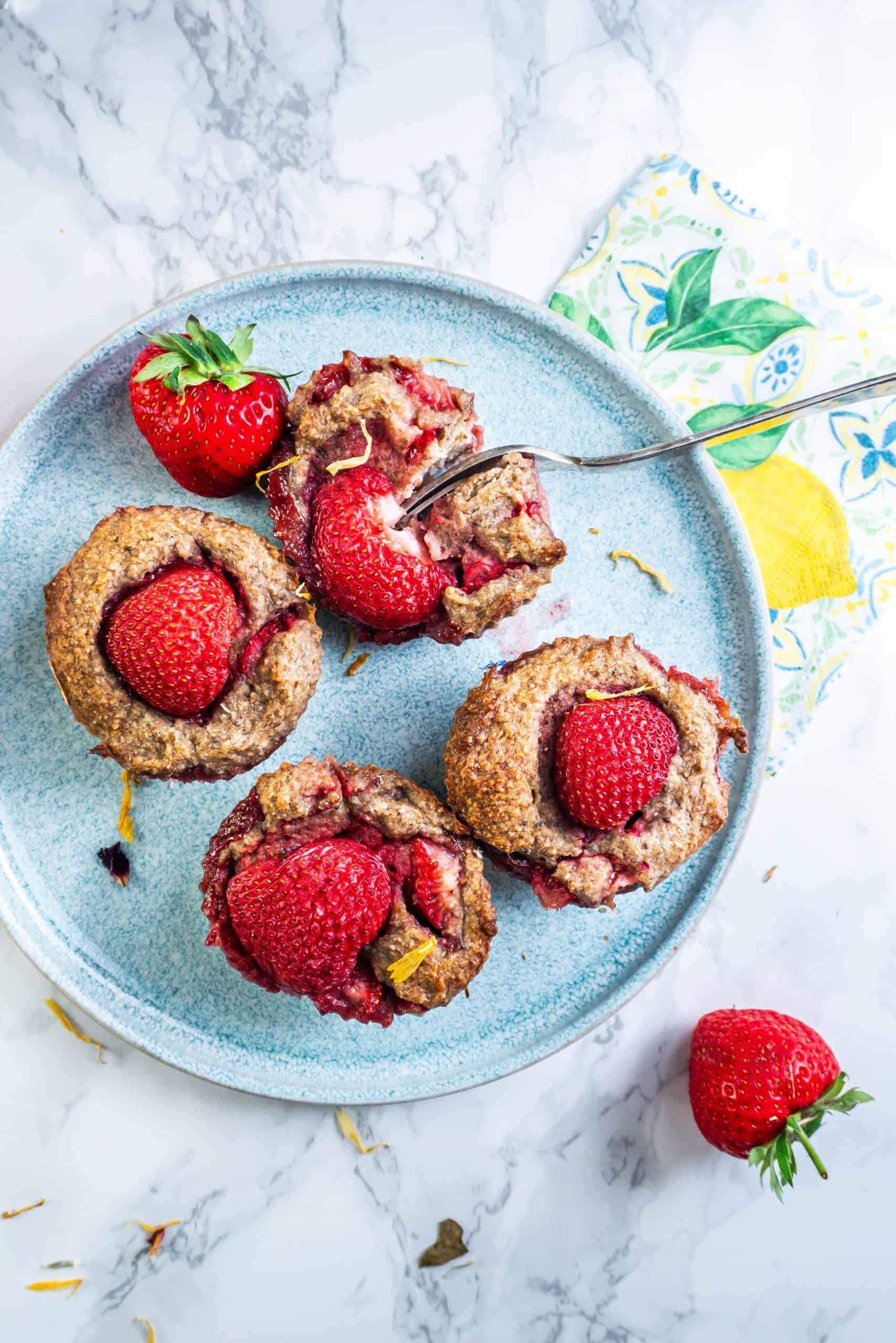 A fork tugging into the Strawberry Banana Muffins on a plate