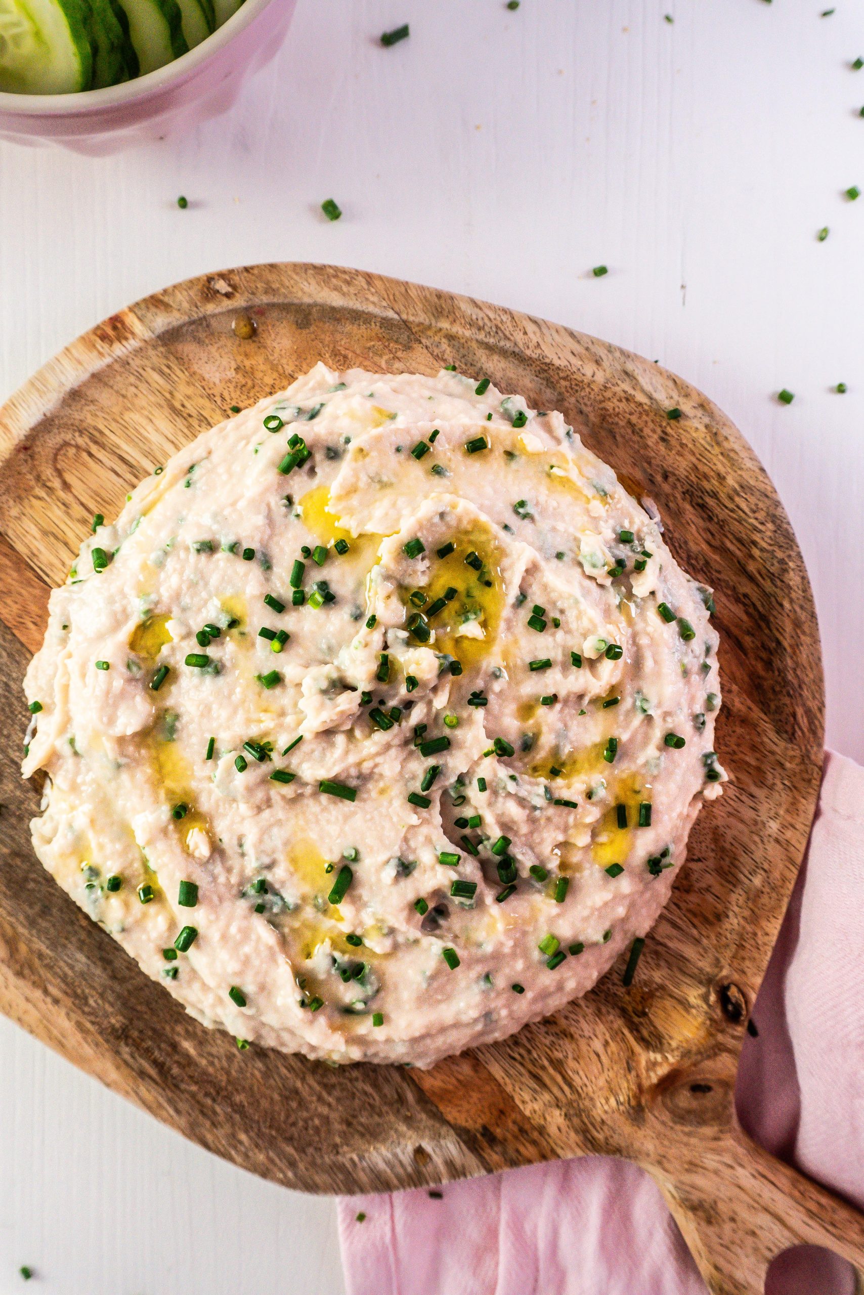 Quick and Easy Butterbean Dip on a wooden plate, garnished with chives and photographed up close