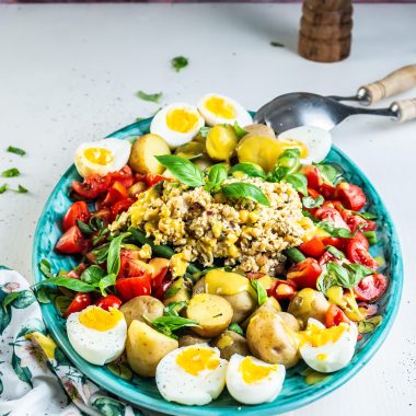 Vegetarian Nicoise Salad being served pretty on a plate with salad tongs visible in the background