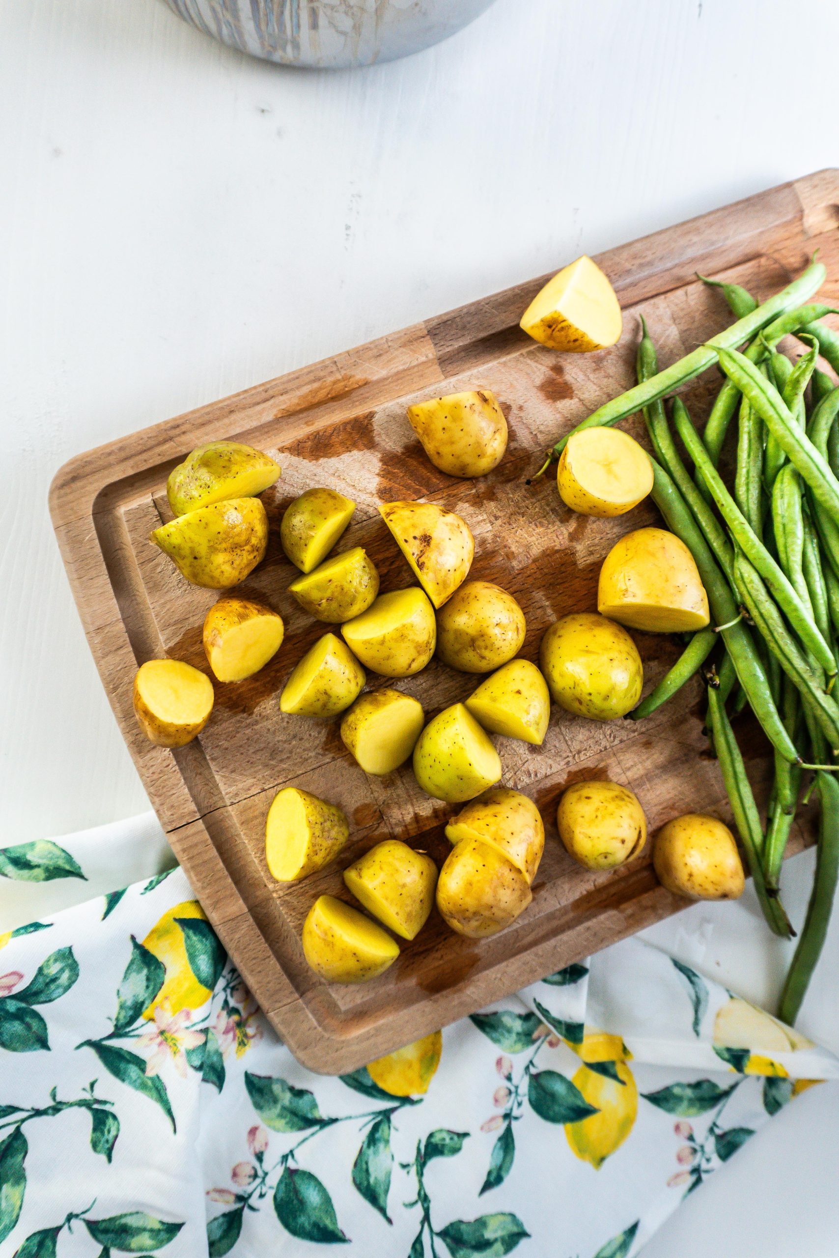 Halve potatoes and green beans on a chopping board