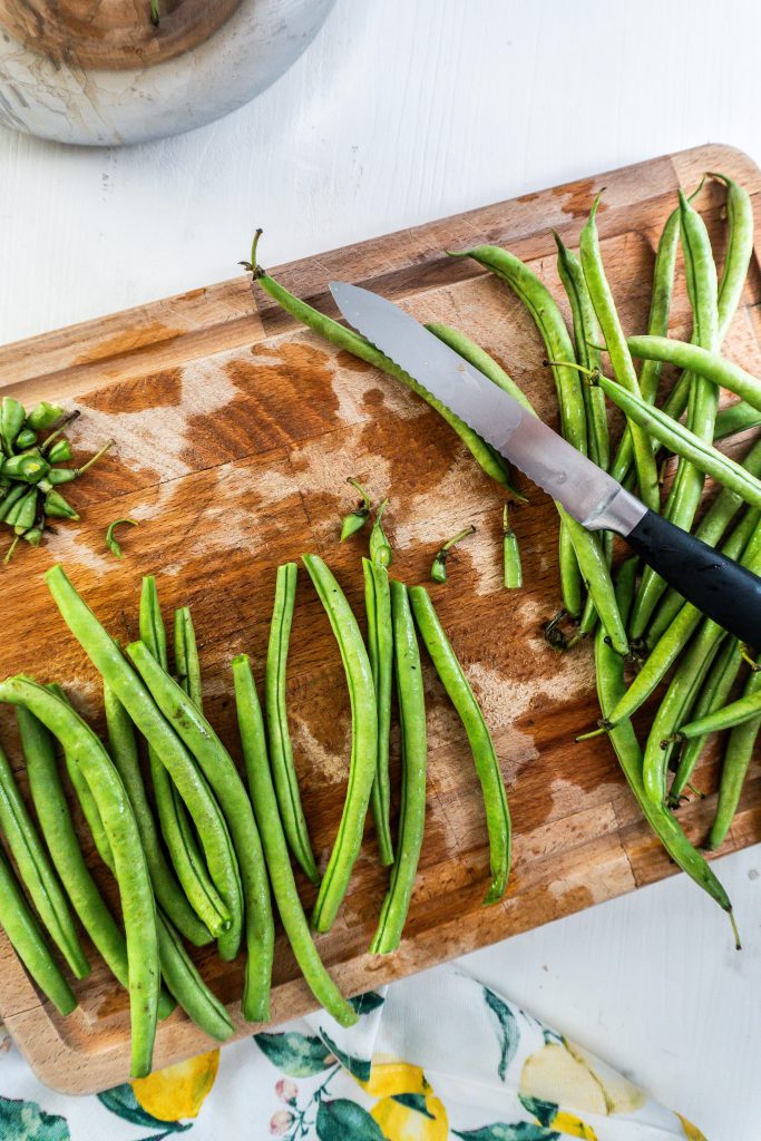 Green beans being cut on a chopping board